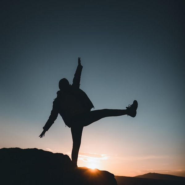 Silhouette of a person in a balanced pose at sunrise.
